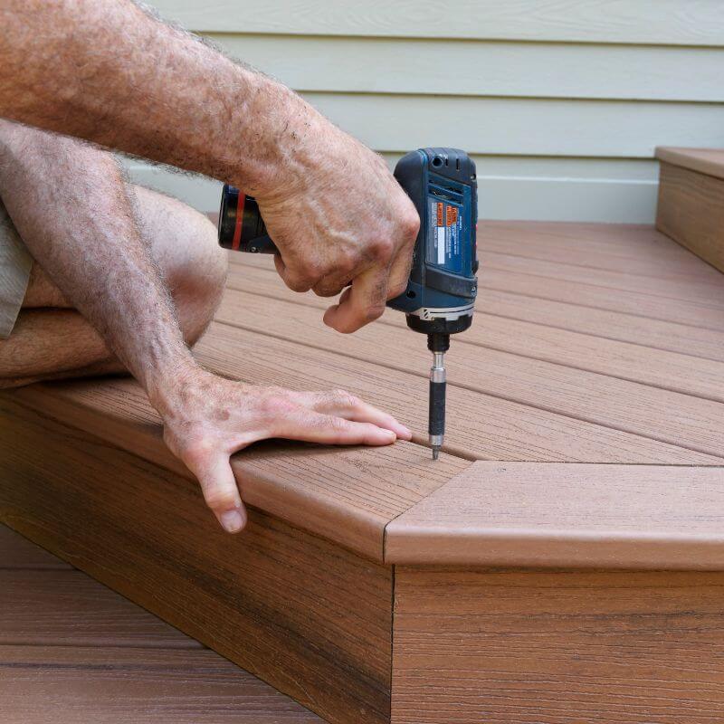 A technician from Kairos Upholstery using a drilling machine to repair wooden decking in Pretoria.