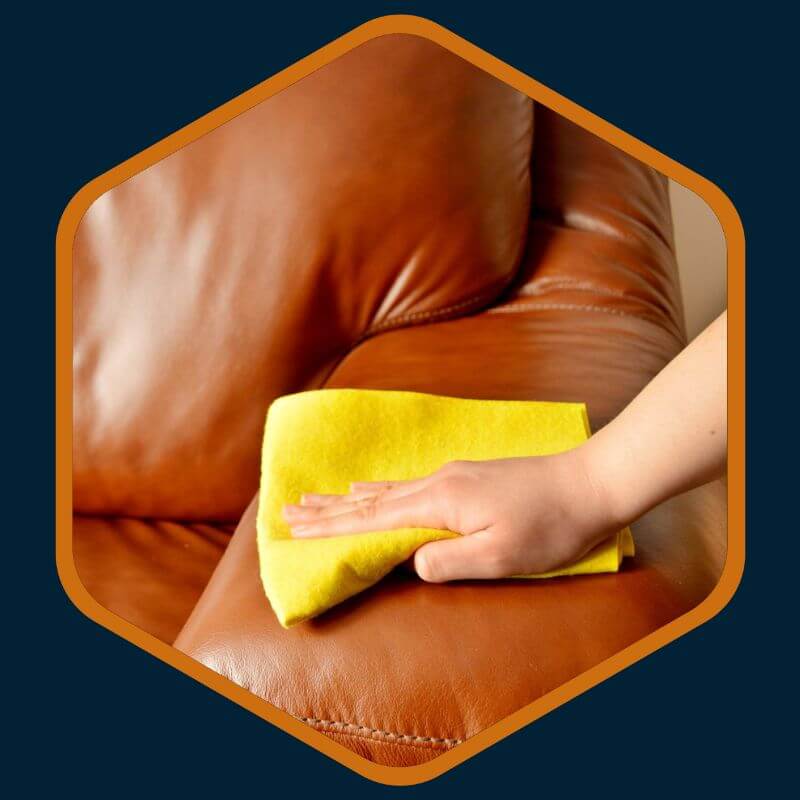 Hand of a technician from Kairos Upholstery cleaning a brown leather couch in Bryanston.