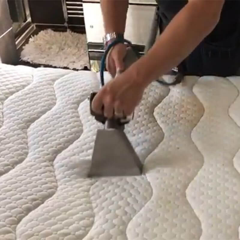 A hand cleaning a mattress using an industrial machine, showcasing Kairos Upholstery's professional mattress cleaning services in Pretoria.