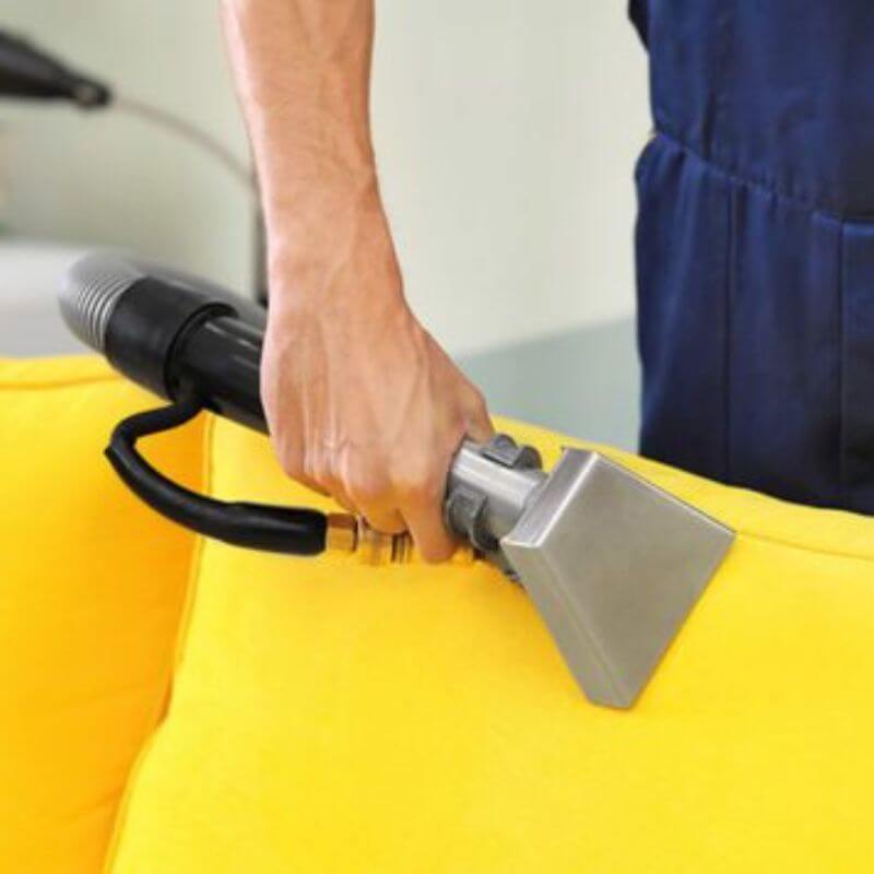 A professional cleaner from Kairos Upholstery providing expert upholstery cleaning services for a couch in Pretoria.