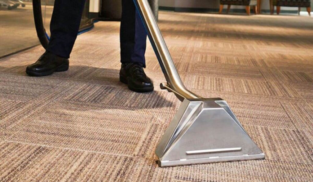 Professional technician cleaning a carpet, highlighting Kairos Upholstery’s carpet cleaning service.
